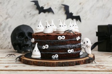 Tatlı Cadılar Bayramı pastası beyaz ahşap masada hayaletler, örümcekler ve kafataslarıyla süslenmiş.
