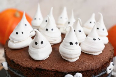 Beyaz arka planda hayaletlerle süslenmiş tatlı Cadılar Bayramı pastası, yakın plan.