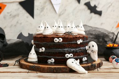 Tatlı Cadılar Bayramı pastası beyaz ahşap masada hayaletler, örümcekler ve gözlerle süslenmiş.