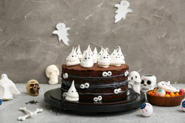 Tatlı Cadılar Bayramı pastası. Gri arka planda örümcekler, şekerler, gözler, kemikler ve kafataslarıyla süslenmiş.