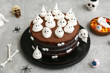 Tatlı Cadılar Bayramı pastası. Gri arka planda hayaletler, gözler, örümcekler, kemikler, kafatasları ve şekerlerle süslenmiş.