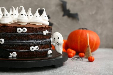 Tatlı Cadılar Bayramı pastası Gri arka planda kremalı hayaletler ve balkabaklarıyla süslenmiş