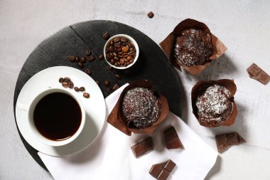 Siyah tahta, çikolatalı kekler ve beyaz arka planda bir fincan kahve.