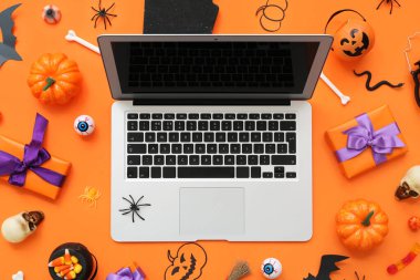 Modern dizüstü bilgisayarlı kompozisyon, Cadılar Bayramı için hediyeler ve dekorasyonlar renk arka planında