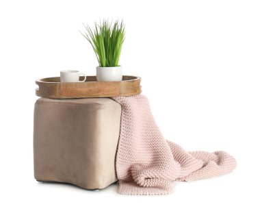 Ahşap tepsi, bitki, fincan ve ekoseli beyaz arka planda şık bir puf