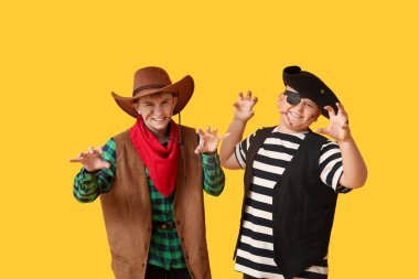 Cadılar Bayramı partisi için sarı arka planda giyinmiş şirin, mutlu çocuklar.