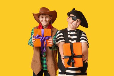 Cadılar Bayramı partisi için sarı arka planda hediye kutuları olan sevimli mutlu çocuklar.