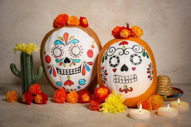 Kafatası boyalı balkabakları, yanan mumlar, çiçekler ve açık arkaplanda dekor. El Dia de Muertos