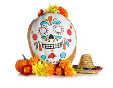 Kafatası boyanmış balkabağı, mini sombrero ve beyaz arka planda çiçekler. El Dia de Muertos