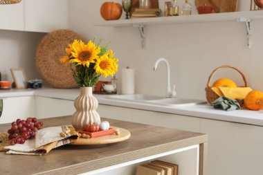 Masada sonbahar çiçekleri, üzümler ve balkabaklarıyla aydınlık mutfağın içi.