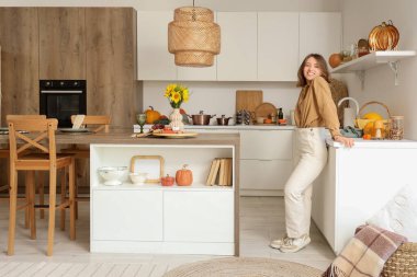 Mutfakta sonbahar süslemeleriyle güzel genç bir kadın.