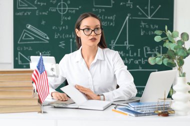 Sınıftaki masada elinde not defteri ve rüşvetle bayan öğretmen. Yolsuzluk kavramı