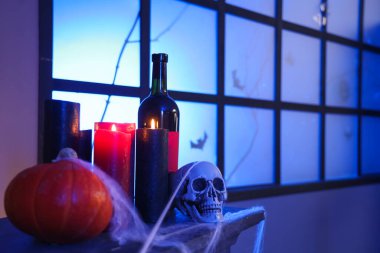 Geceleri pencerenin yanındaki şöminenin üzerinde mum ve şarap bulunan Cadılar Bayramı süslemeleri.