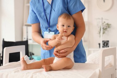 Doğum hastanesindeki masada yeni doğmuş bebeği olan genç hemşire.