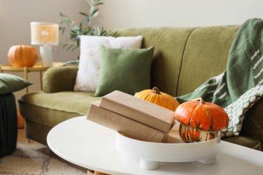 Oturma odasındaki masada kitap ve balkabağı dolu tepsi, yakın plan.