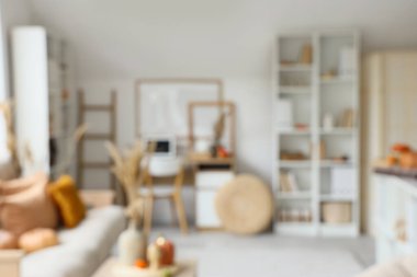 Sonbahar dekoru, işyeri ve raf üniteleriyle aydınlık oturma odasının bulanık görüntüsü