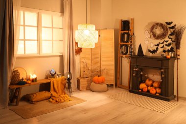 Cadılar Bayramı süslemeleri ve şenlikli oturma odasında parlayan lambalar olan şömine.