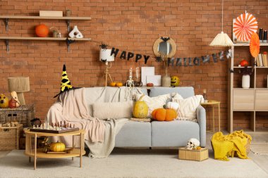 Gri kanepe, balkabağı ve Cadılar Bayramı süslemeleriyle dolu bir oturma odası.