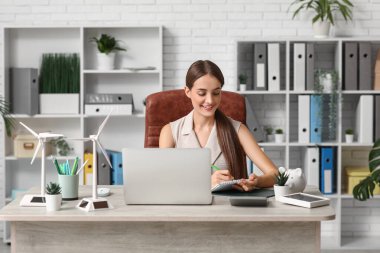 Ofiste çalışan rüzgar türbini modelli kadın mühendis.