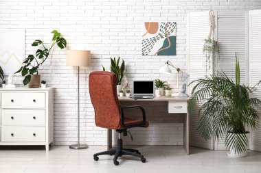 Çalışma alanı, katlama ekranı ve yeşil bitkilerle ofis içi