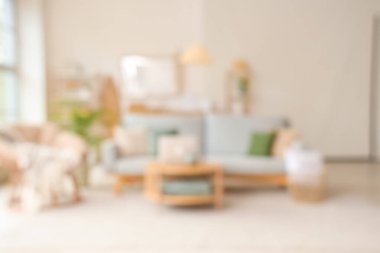 Kahve masasında gri kanepe ve dizüstü bilgisayarla aydınlık oturma odasının bulanık görüntüsü