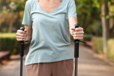 Güzel, olgun bir kadın parkta sırıklarla antrenman yapıyor, yakın plan.