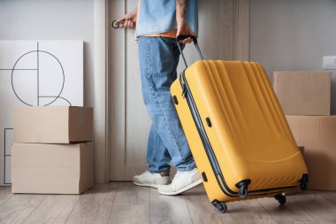 Taşındığı gün valizli genç bir adam salonun kapısını açıyor.