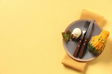 Sarı arka planda kafatası ve balkabağı ile Cadılar Bayramı kutlaması için şenlik masası