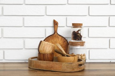 Tahta kaseler, yemek ve tepsi beyaz tuğla duvarın yanındaki masada.