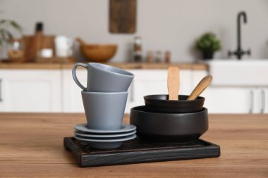 Mutfaktaki ahşap tezgahın üzerinde çanaklar, fincanlar ve tabaklar var.