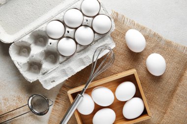 Beyaz arka planda çiğ tavuk yumurtaları olan ahşap bir kutu.