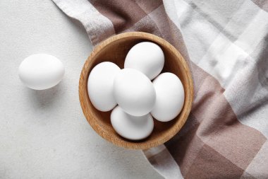 Beyaz arka planda çiğ tavuk yumurtası olan ahşap kase.