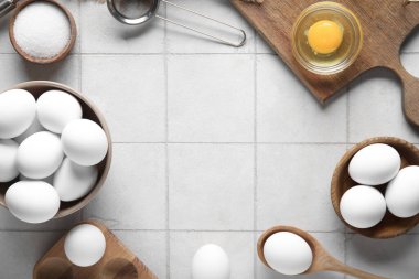 Tabaklardan yapılmış çerçeve ve ahşap tutacaklı beyaz fayanslı çiğ tavuk yumurtaları.