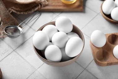 Beyaz fayanslı çiğ tavuk yumurtalı kase ve ahşap tutucu