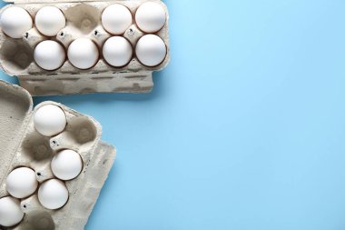 Mavi arka planda çiğ tavuk yumurtası tutanlar