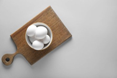 Gri arka planda çiğ tavuk yumurtası ile kase