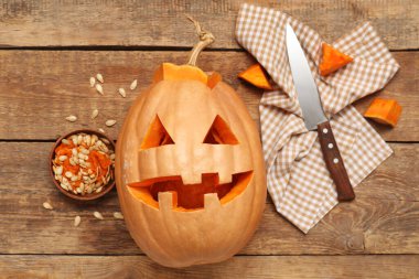 Bıçak, tohum ve peçeteyle oyulmuş Cadılar Bayramı balkabağı ahşap arka planda