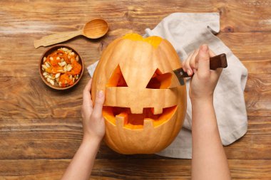 Balkabağı oyan bir kadın ve tahta arka planda bir kase tohum.