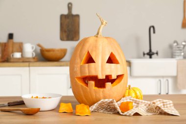 Cadılar Bayramı balkabağı oyulmuş. Mutfakta bir kase tohum ve kaşıkla.