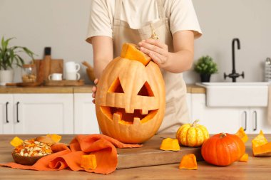 Cadılar Bayramı balkabağı oyulmuş bir kadın, mutfakta bir kase tohum ve kaşık.