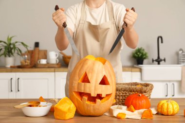 Cadılar Bayramı için mutfak tezgahında bıçaklı balkabağı oyan kadın.
