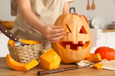 Mutfakta Cadılar Bayramı için balkabağı oyan kadın.