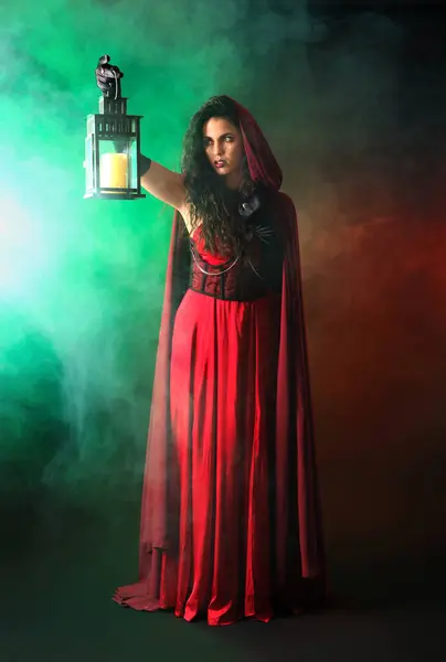 stock image Young witch with lantern in smoke on dark background