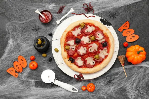 Lezzetli Cadılar Bayramı pizzası, malzemeler ve koyu arkaplanda süslemeler.