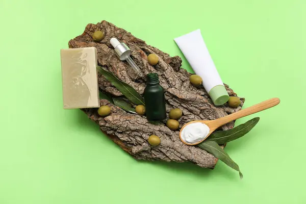 stock image Composition with natural cosmetic products, tree bark and green olives on color background