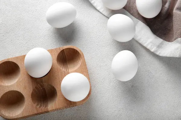 Beyaz arka planda çiğ tavuk yumurtası olan tahta tutucu.