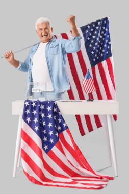 Amerikan bayraklı olgun bir adama oy vermek açık arka plandaki oy sandığının yanında