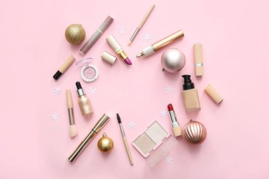 Makyaj ürünlerinden yapılmış çerçeve ve pembe arka planda Noel süslemeleri