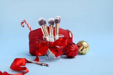 Kozmetik çantalı ve mavi arka planda makyaj fırçalı güzel Noel süslemeleri