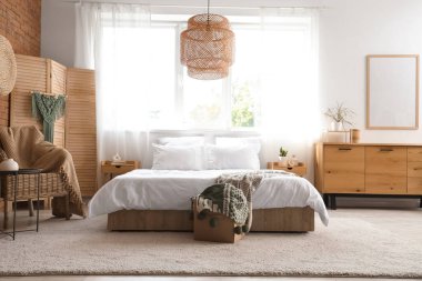 Konforlu yatak odasının içi ve pencerenin yanındaki ahşap katlanır ekran.